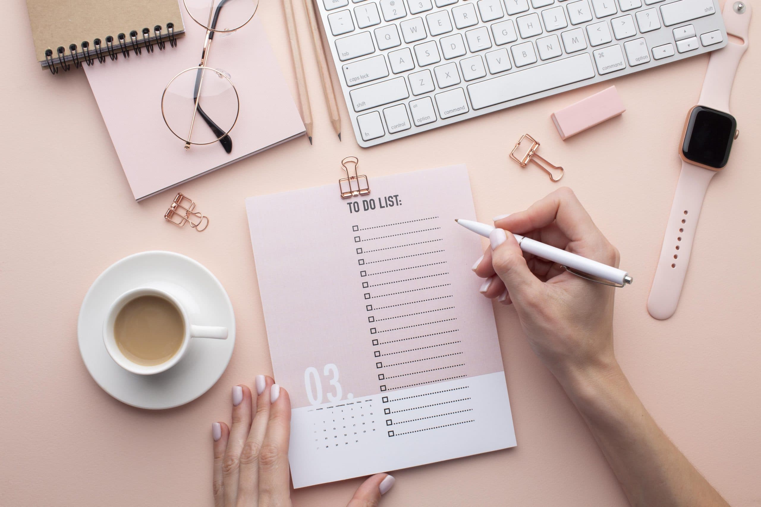 A person holding a pen above a to-do list paper to write down the steps for choosing the right counsellor. Several items, such as a coffee mug, watch, glasses, keyboard and notebooks are on the table.