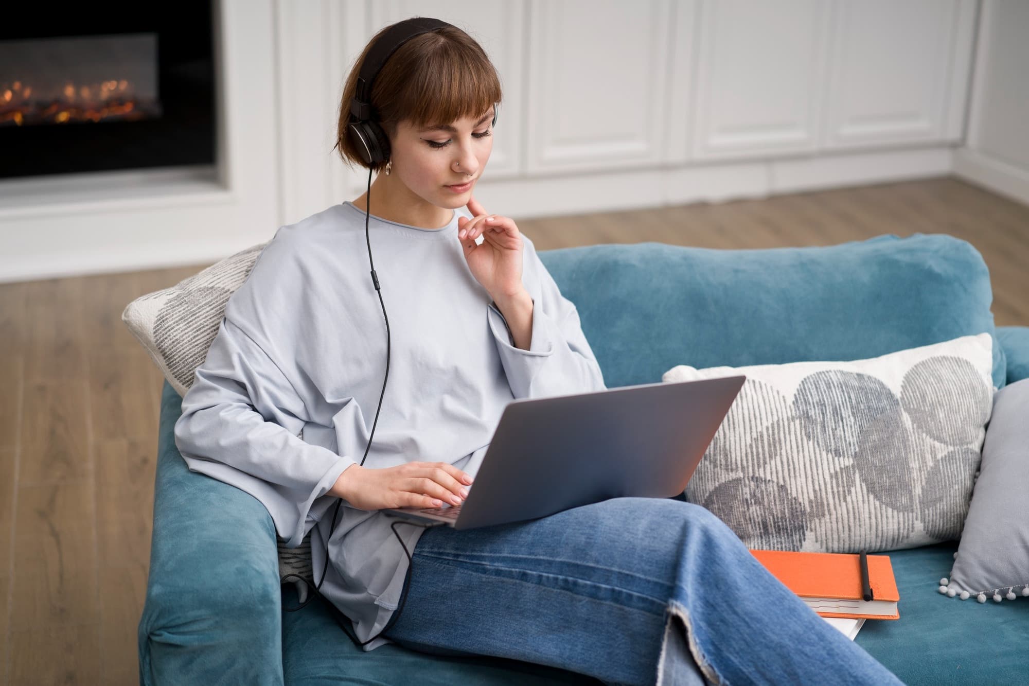 A person sits on the couch with a laptop to attend an online counselling session.