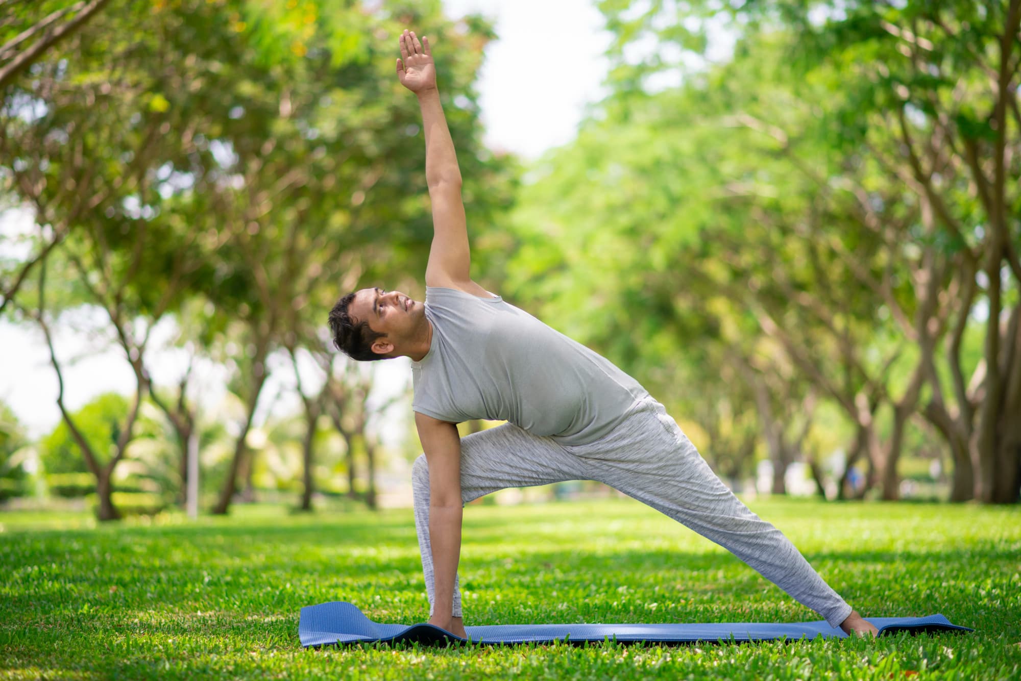 A man doing yoga asanas in a city park to cope with job loss and anxiety.