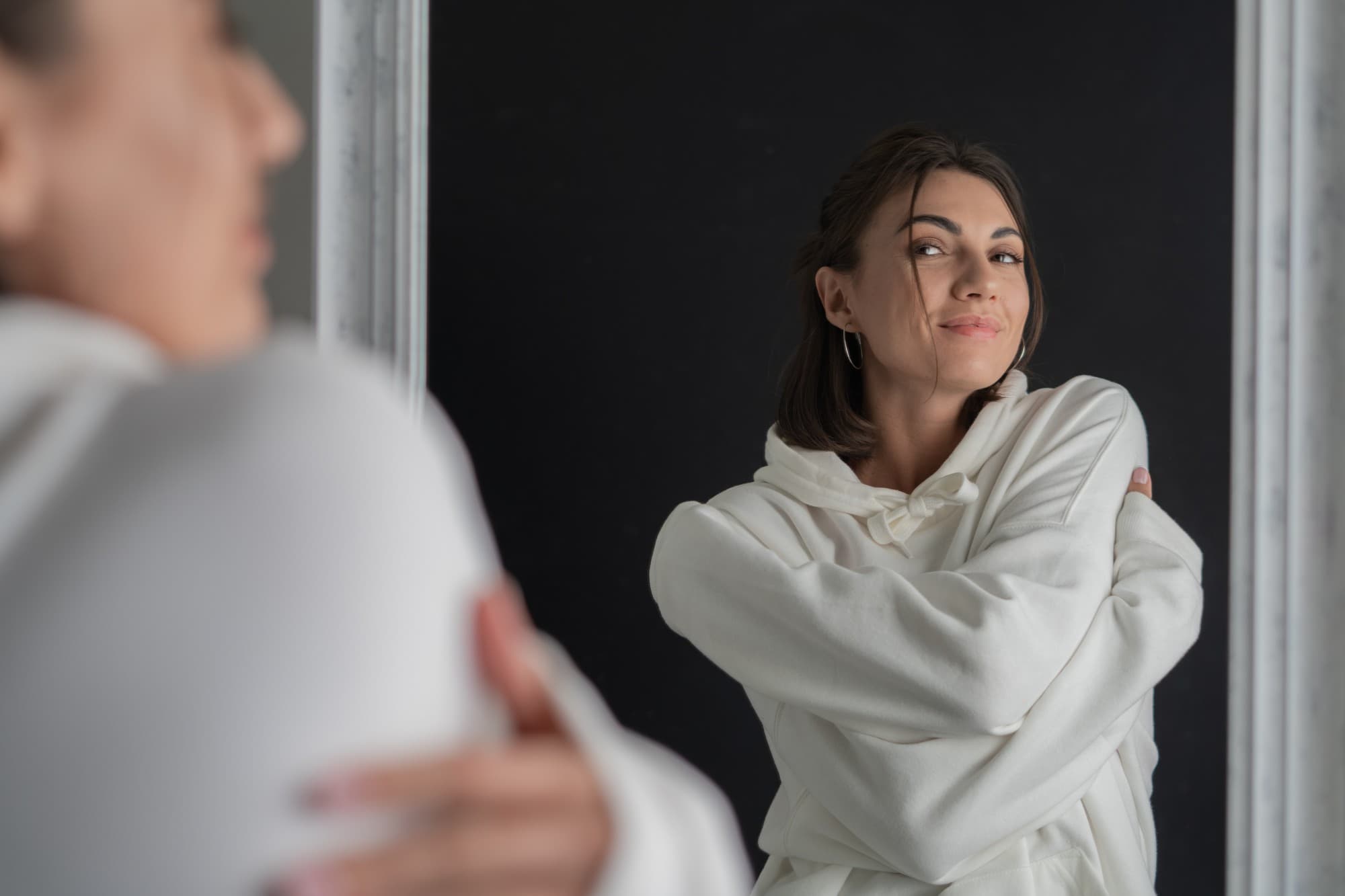 A woman hugging herself, showing self-love and care after learning self-care skills in therapy.