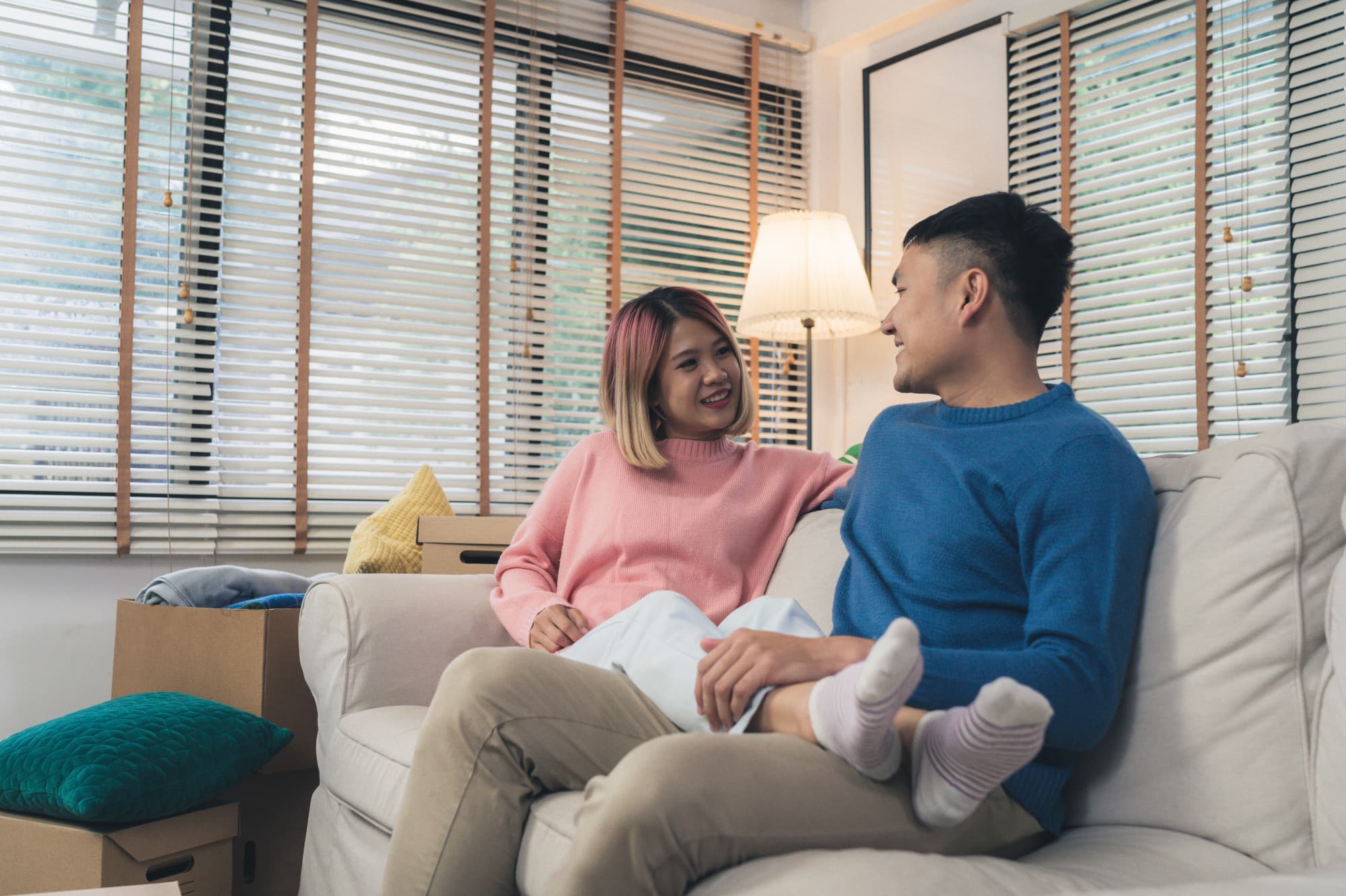 An individual approaching their partner seated on the couch to encourage them to speak to a therapist in Singapore.