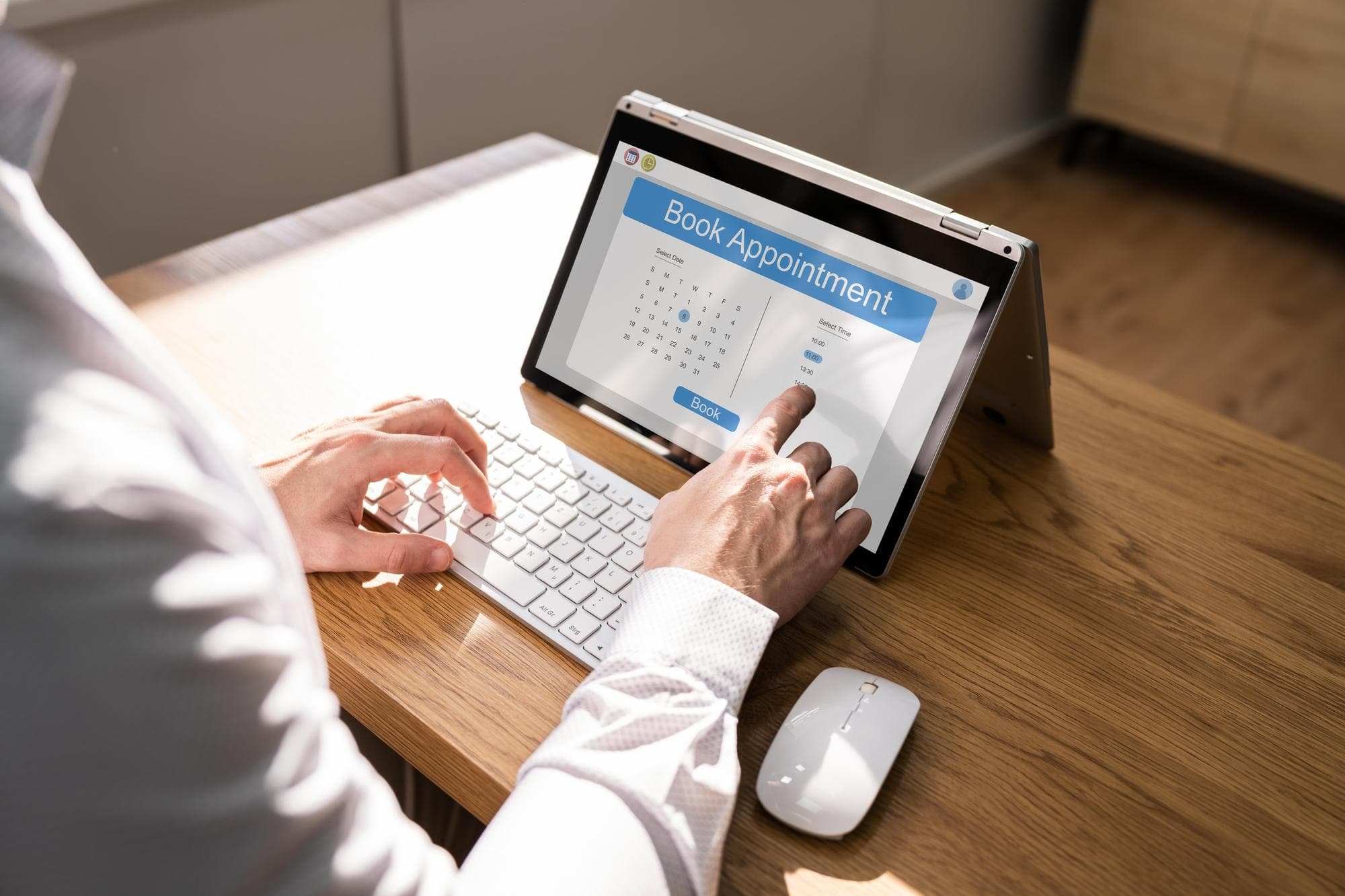 A person sitting on a chair and booking a psychologist appointment on a laptop.