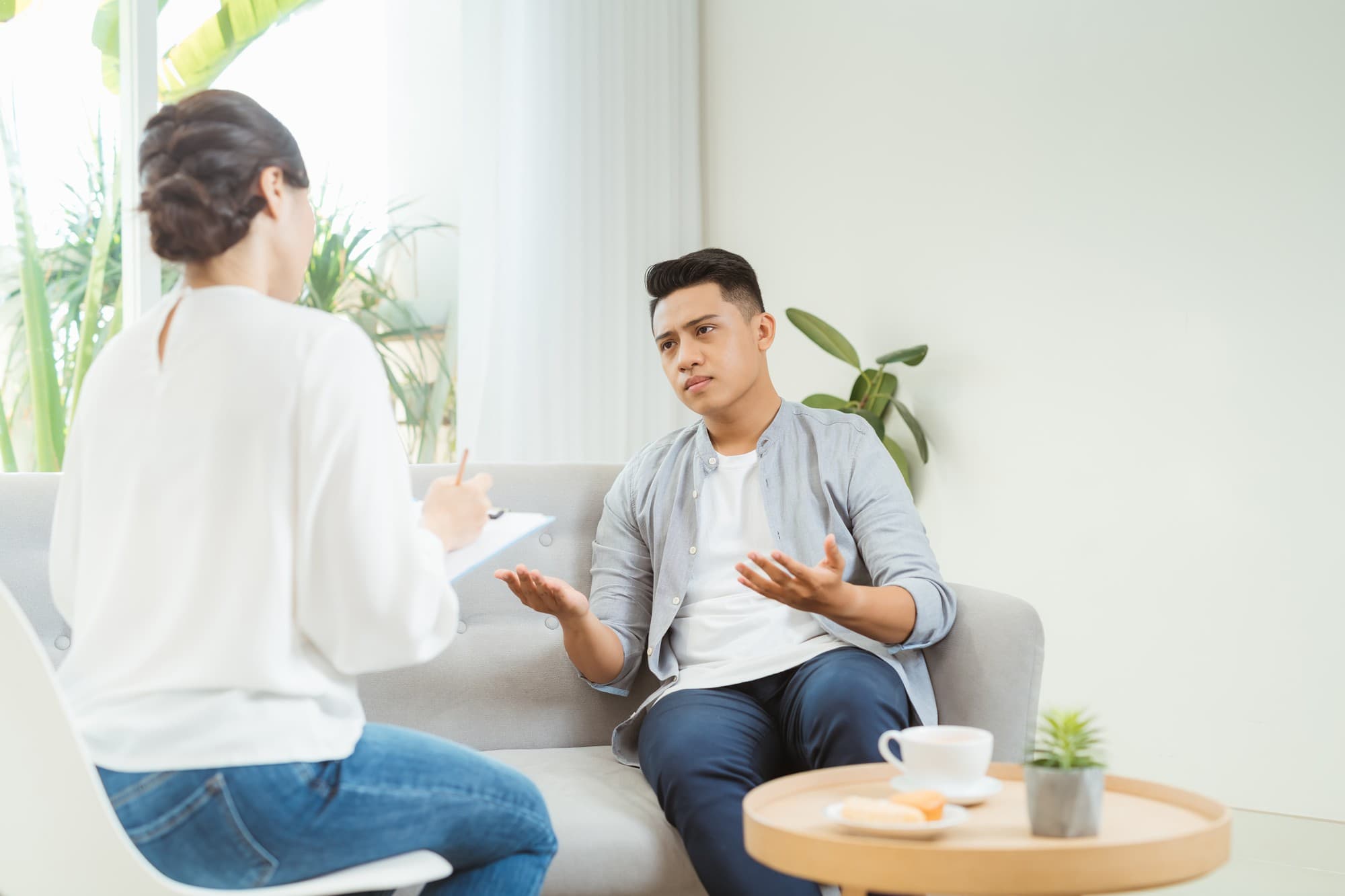 A man is talking to a therapist during therapy to cope with his emotions and negative thought processes.