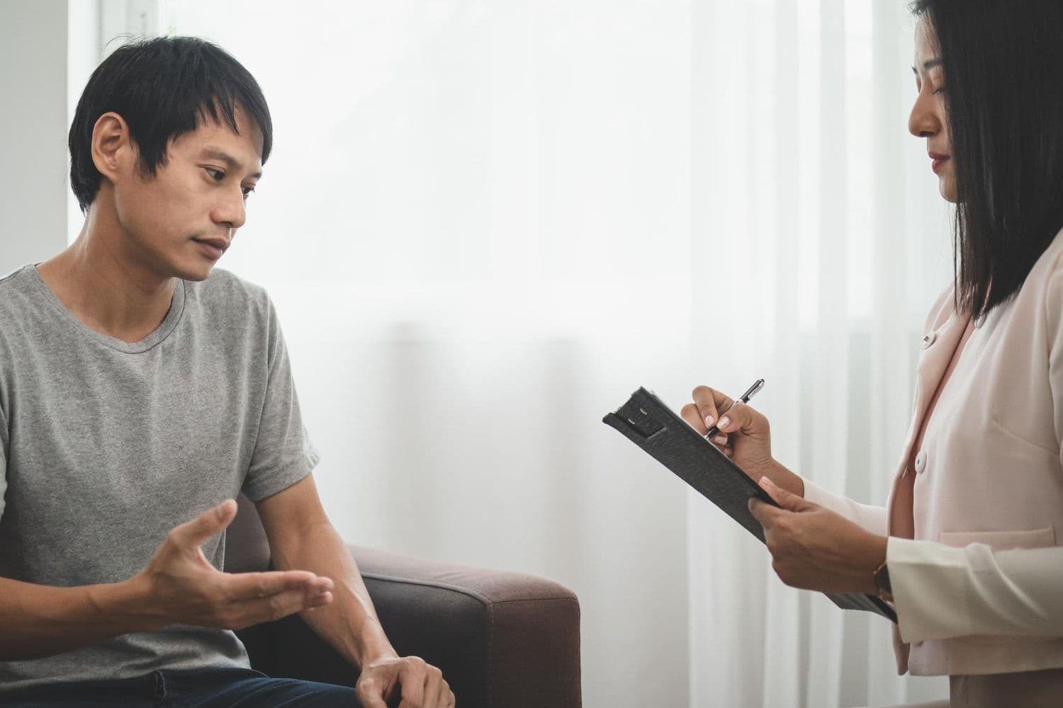 A female therapist listens as a male client opens up during a therapy session.