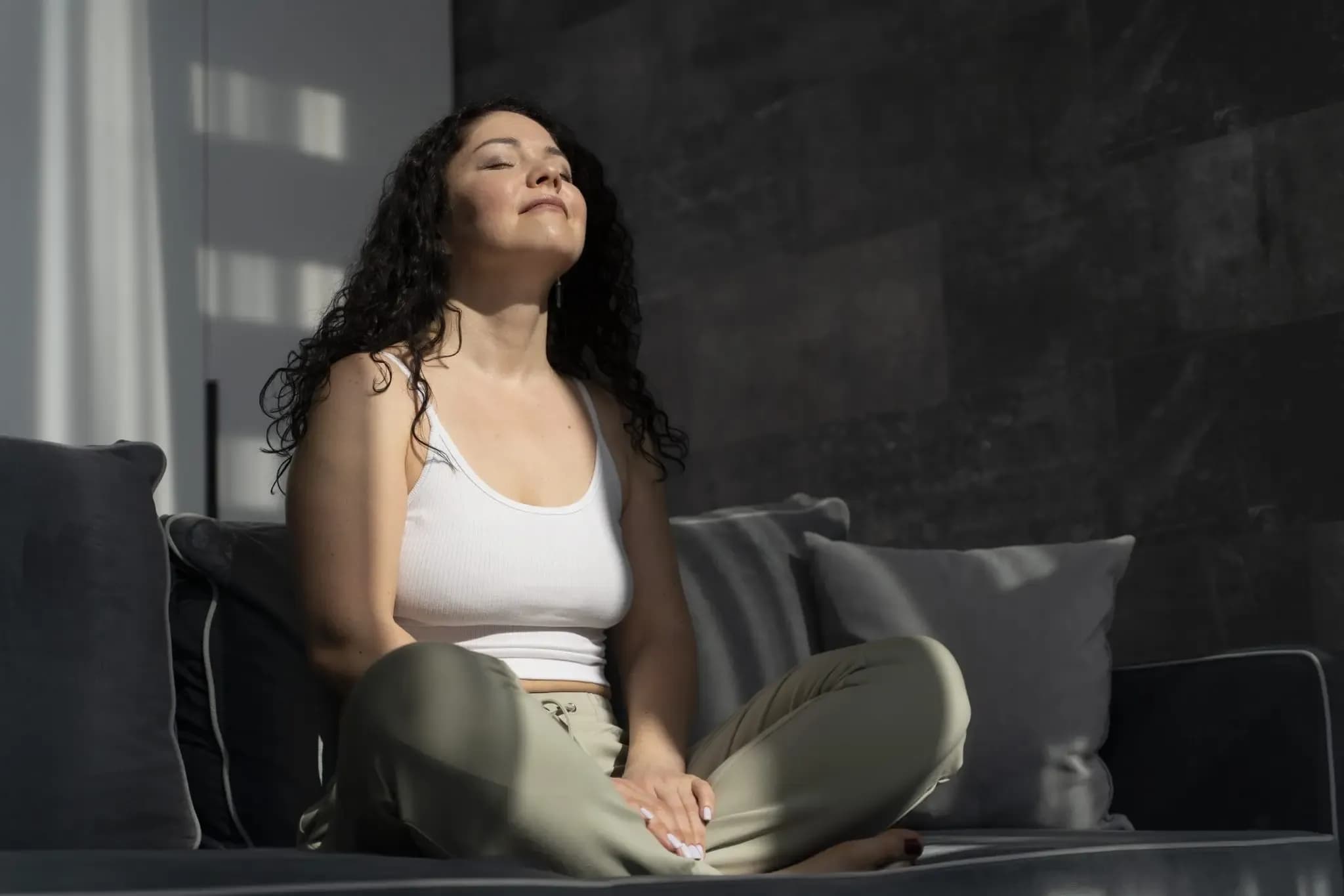 A person sitting on couch and deep breathing to overcome anxiety.