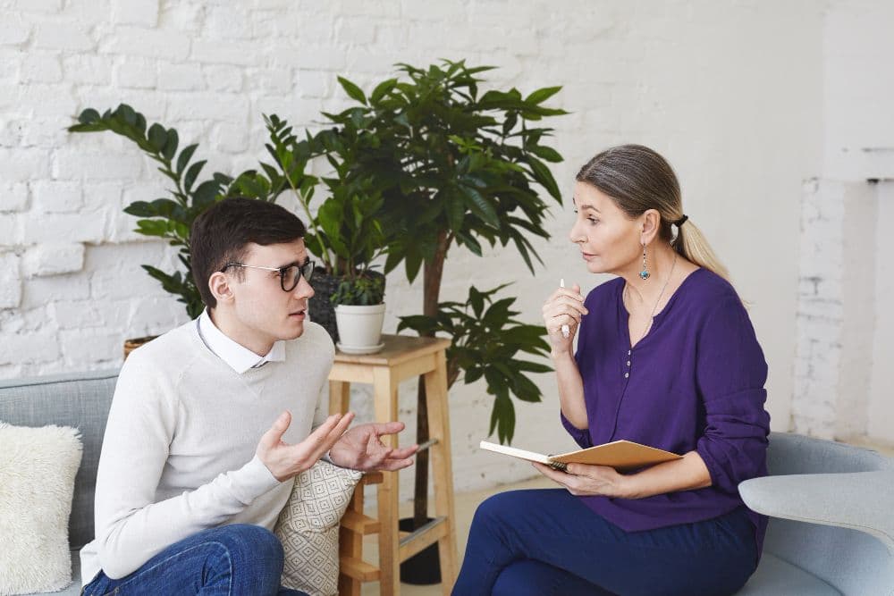 A person discussing behavioural therapy techniques with their psychologist during a session.