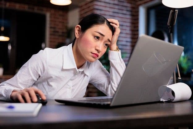 A stressed employee in a corporate setting showing signs of stress and burnout, showing the need for employee assistance programs.