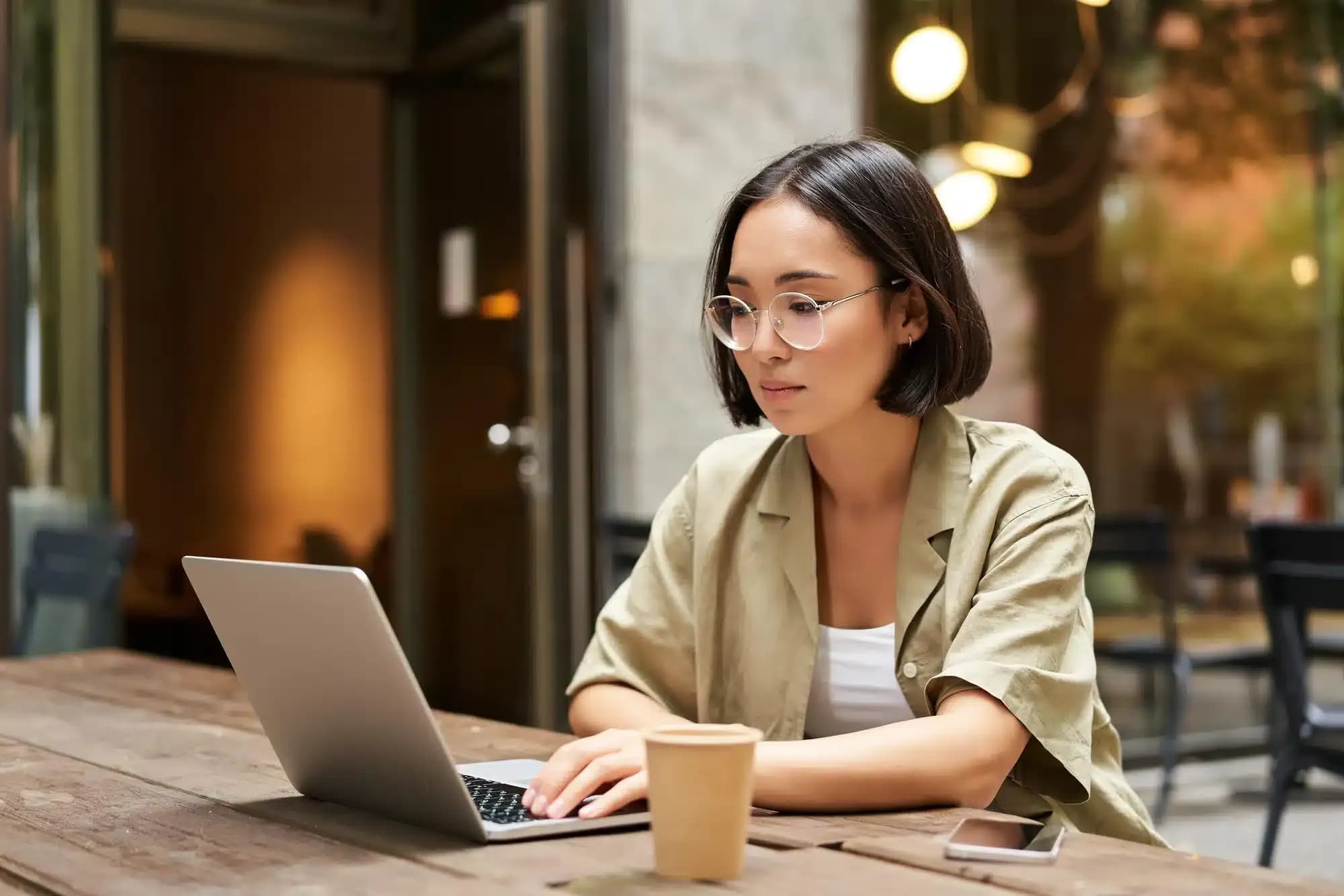 A person sitting at a cafe with their laptop - searching for the right therapist in Singapore.