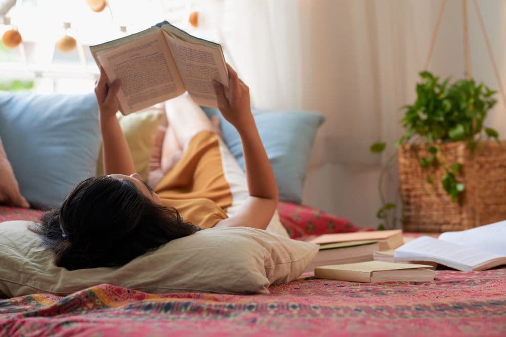 A person lying down and reading a book as a coping skill they learnt during online counselling for sleep issues.