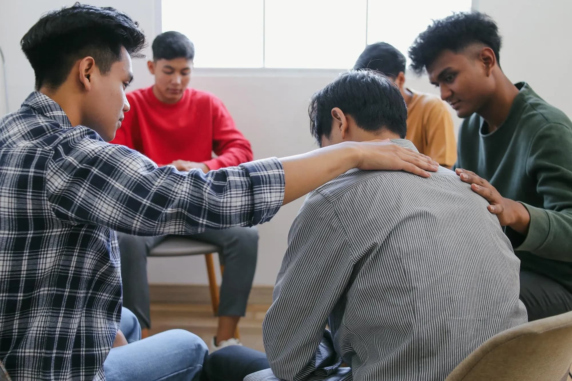 Participants of a group therapy session offering comfort and support to each other, breaking mental health stigma in Singapore.