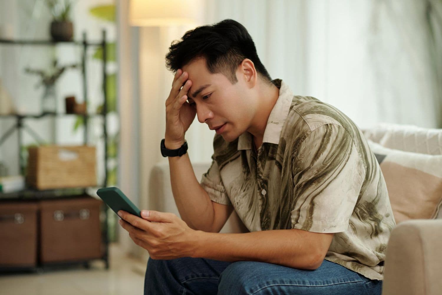 A man staring at his phone and waiting for a text after being ghosted by his partner.
