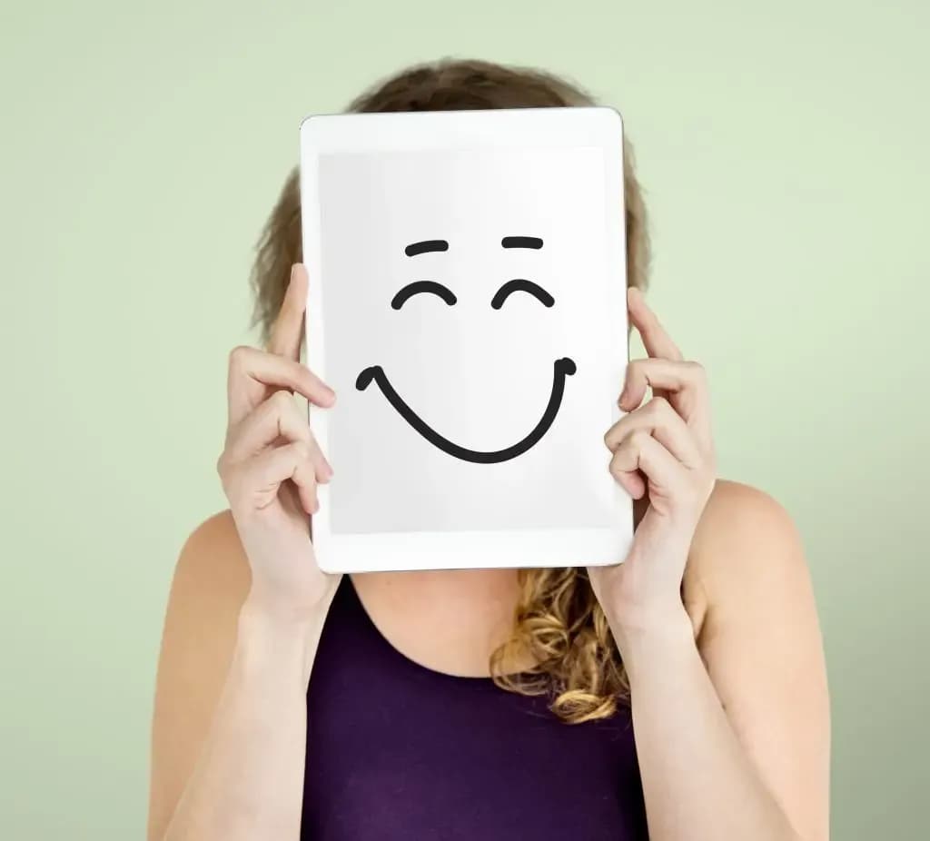 Face with a happy mask in front to indicate compensation in schema therapy.