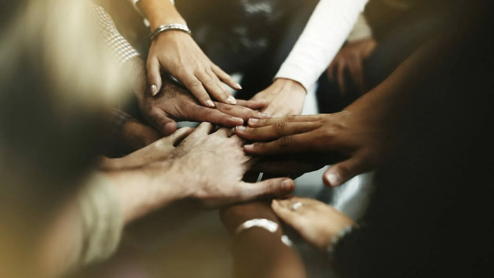 Psychologist in Singapore - TYHO community. Multiple hands joined together on top of each other to signify unity.