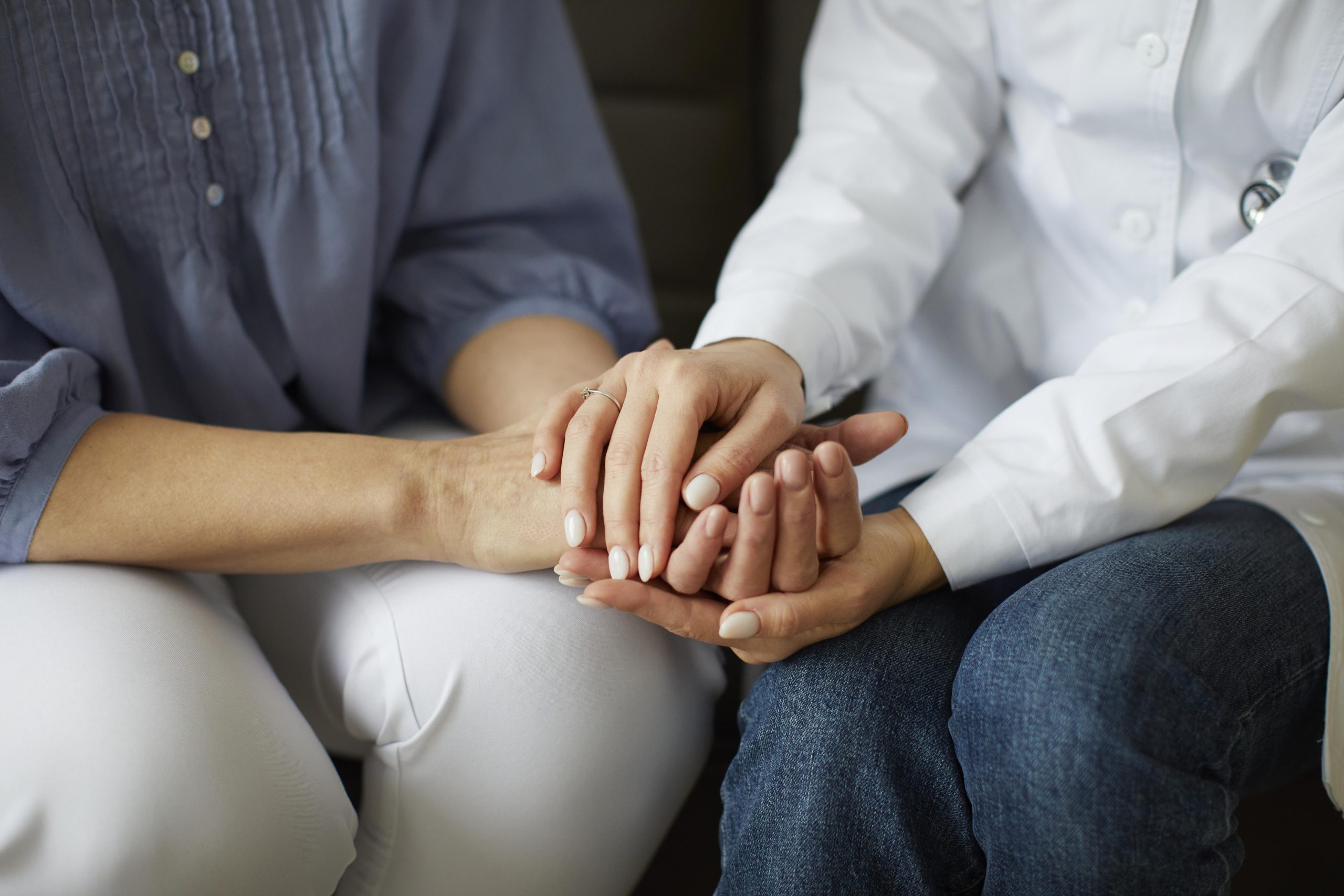 A counsellor holding a client’s hand for support during mental health counselling in Singapore.