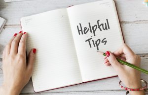 A pair of hands holding a notebook with the text “helpful tips” for finding a therapist in Singapore.
