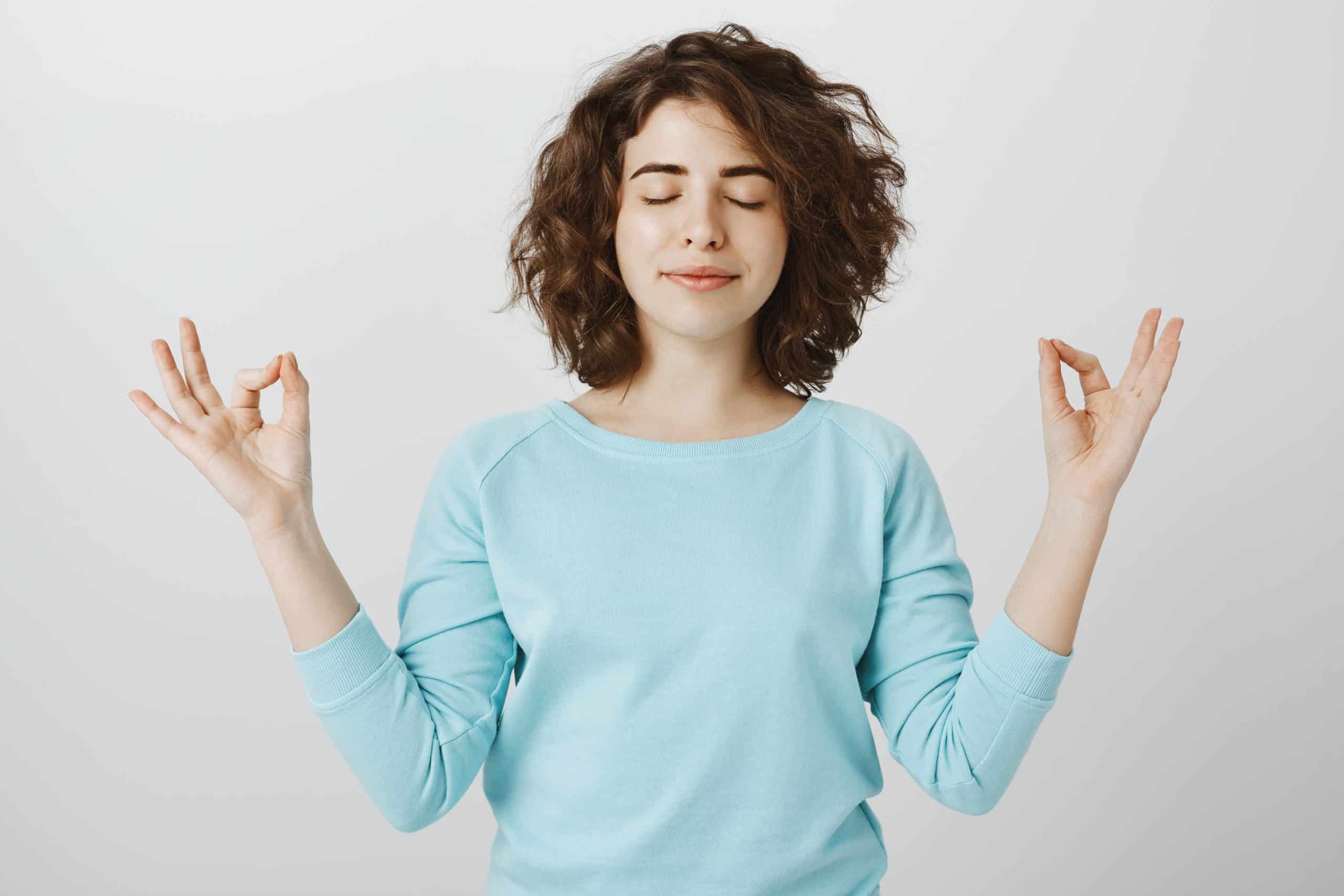 A woman looking peaceful, holding the mediation pose with eyes closed to indicate mental resilience.