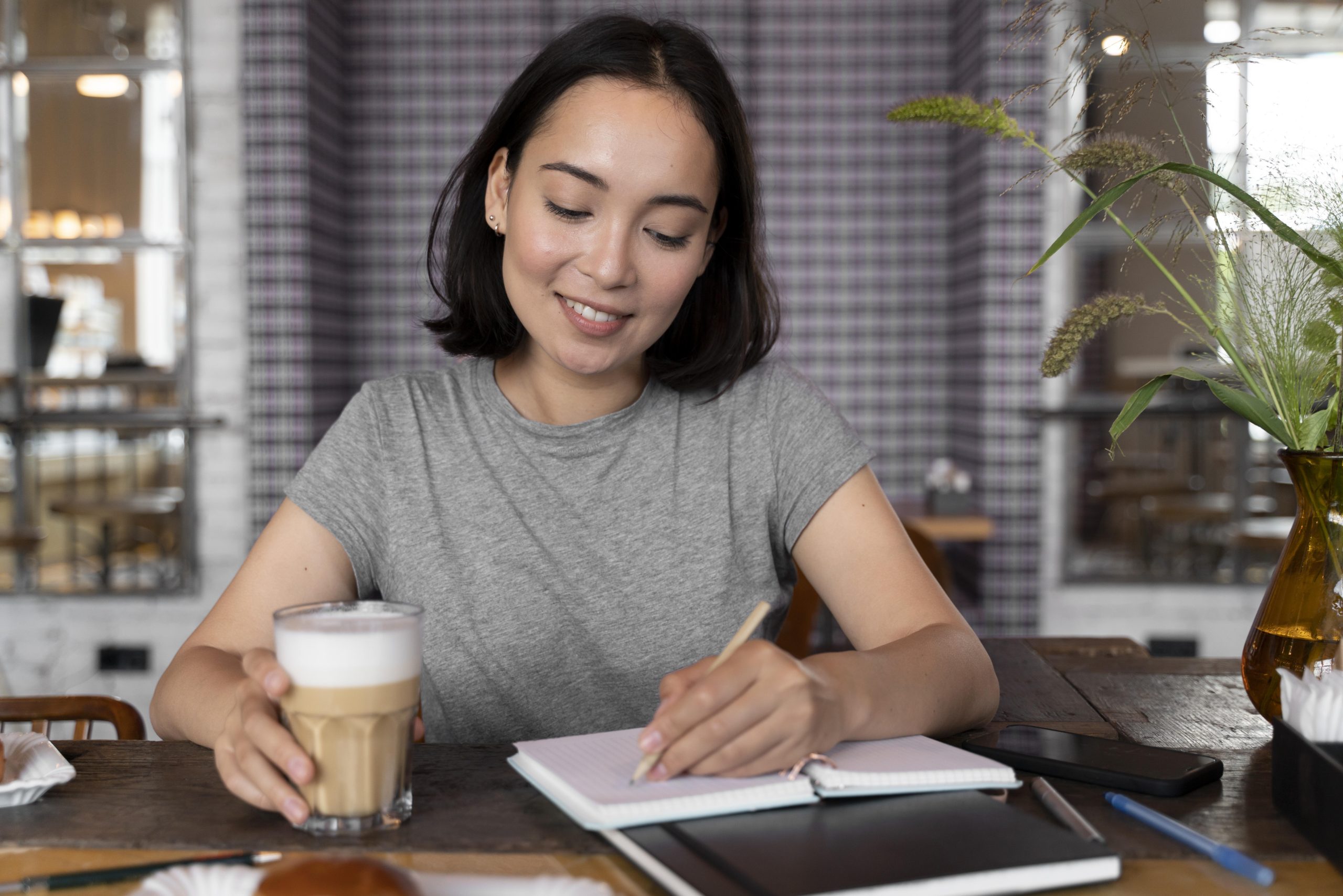 A person smiling with coffee and journalling about how to overcome anxiety.