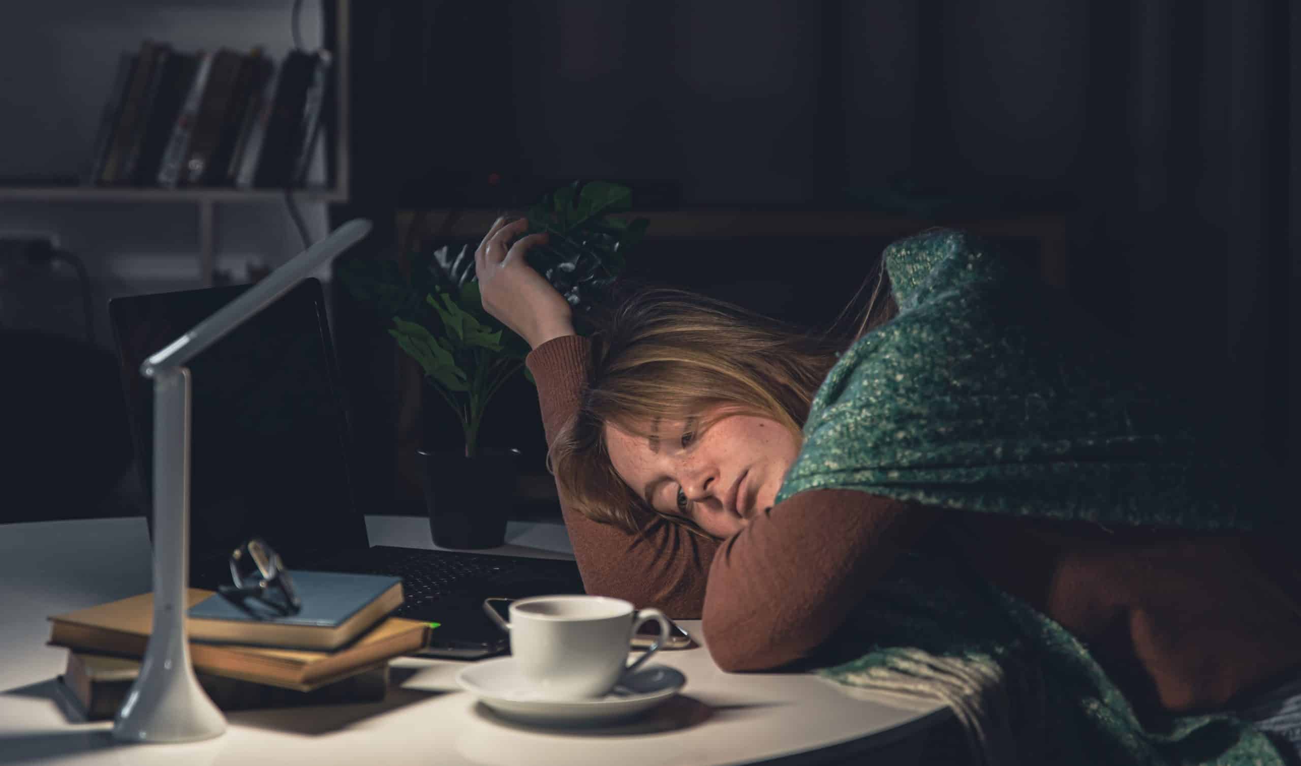 A person laying on the work desk unable to fall asleep due to a psychological disorder called insomnia.