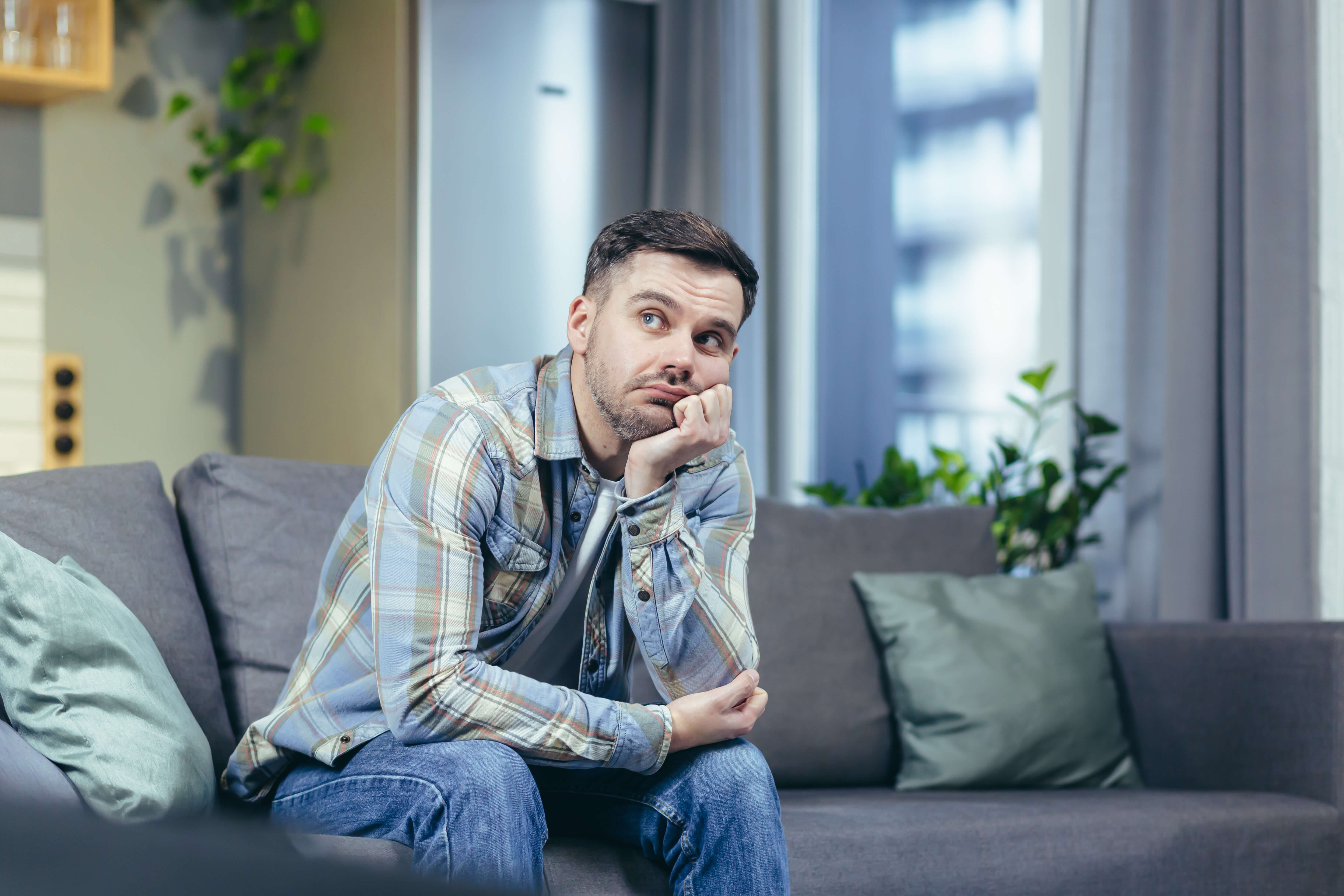 A man sitting on couch and wondering if depression is a mental illness
