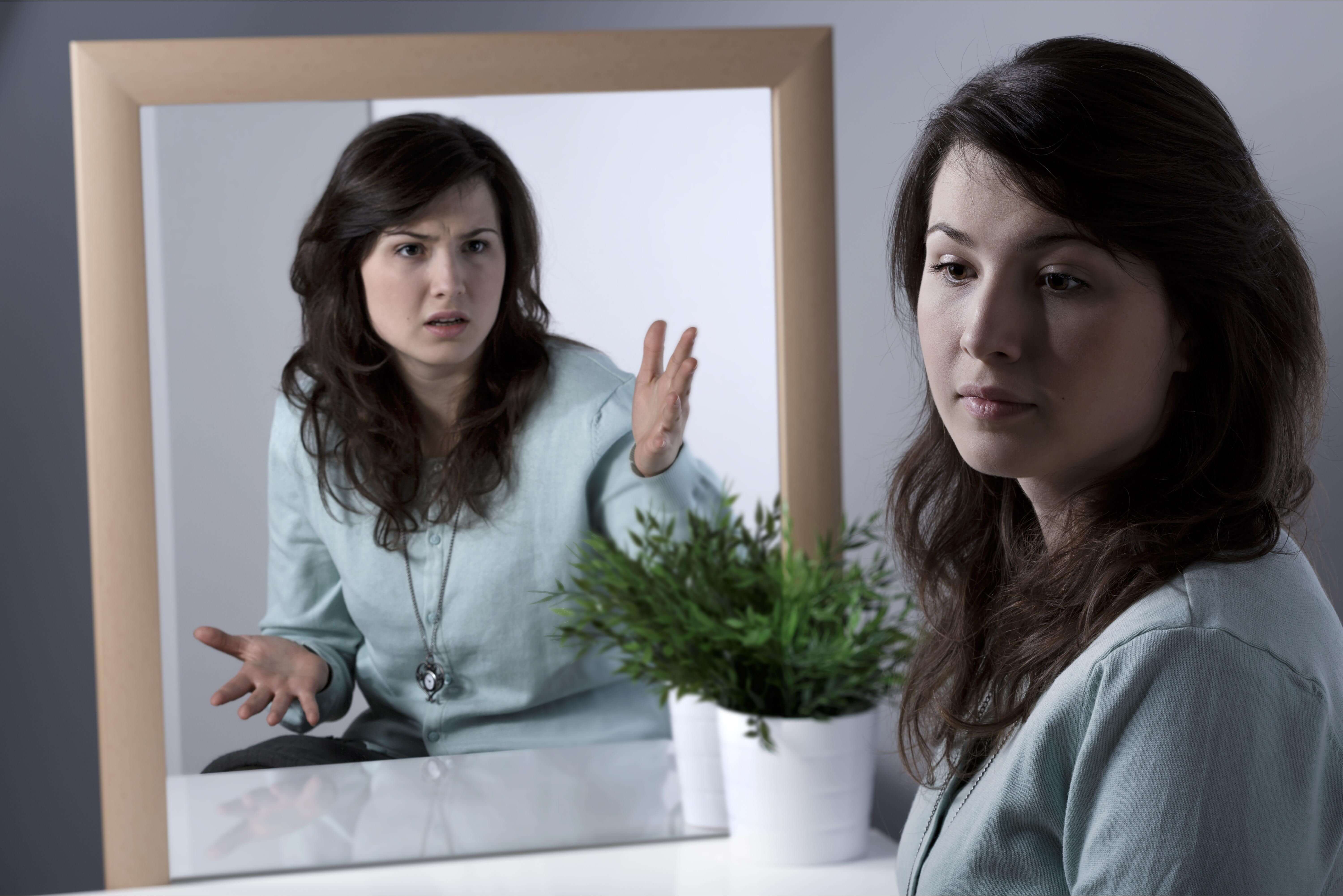 A person looking at their reflection that seems to be very critical, indicating signs of depression