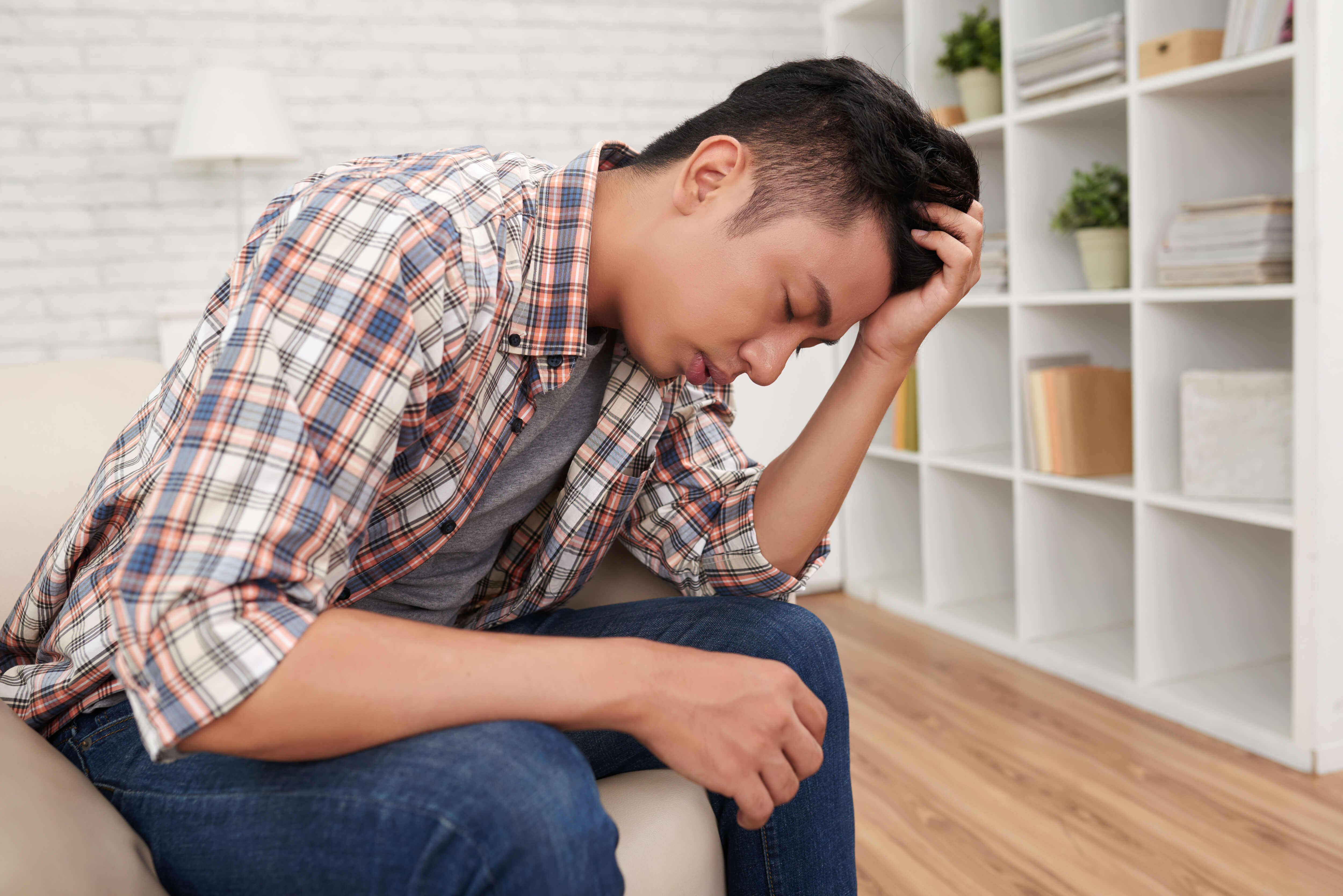 A man sitting on the couch feeling depressed and looking to take a depression test online