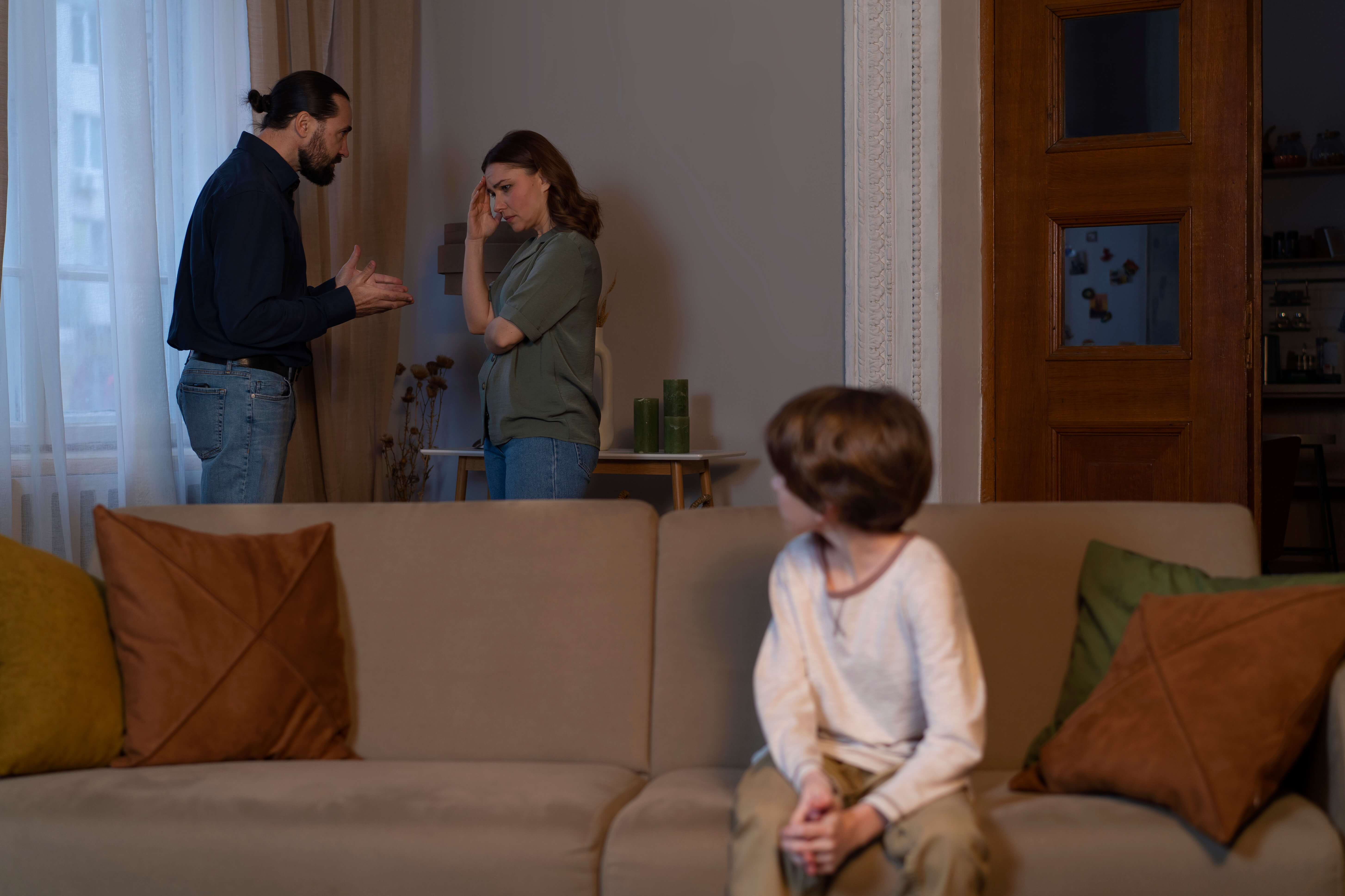 Family fighting and a child sitting on the couch, ready to book a trauma therapy session