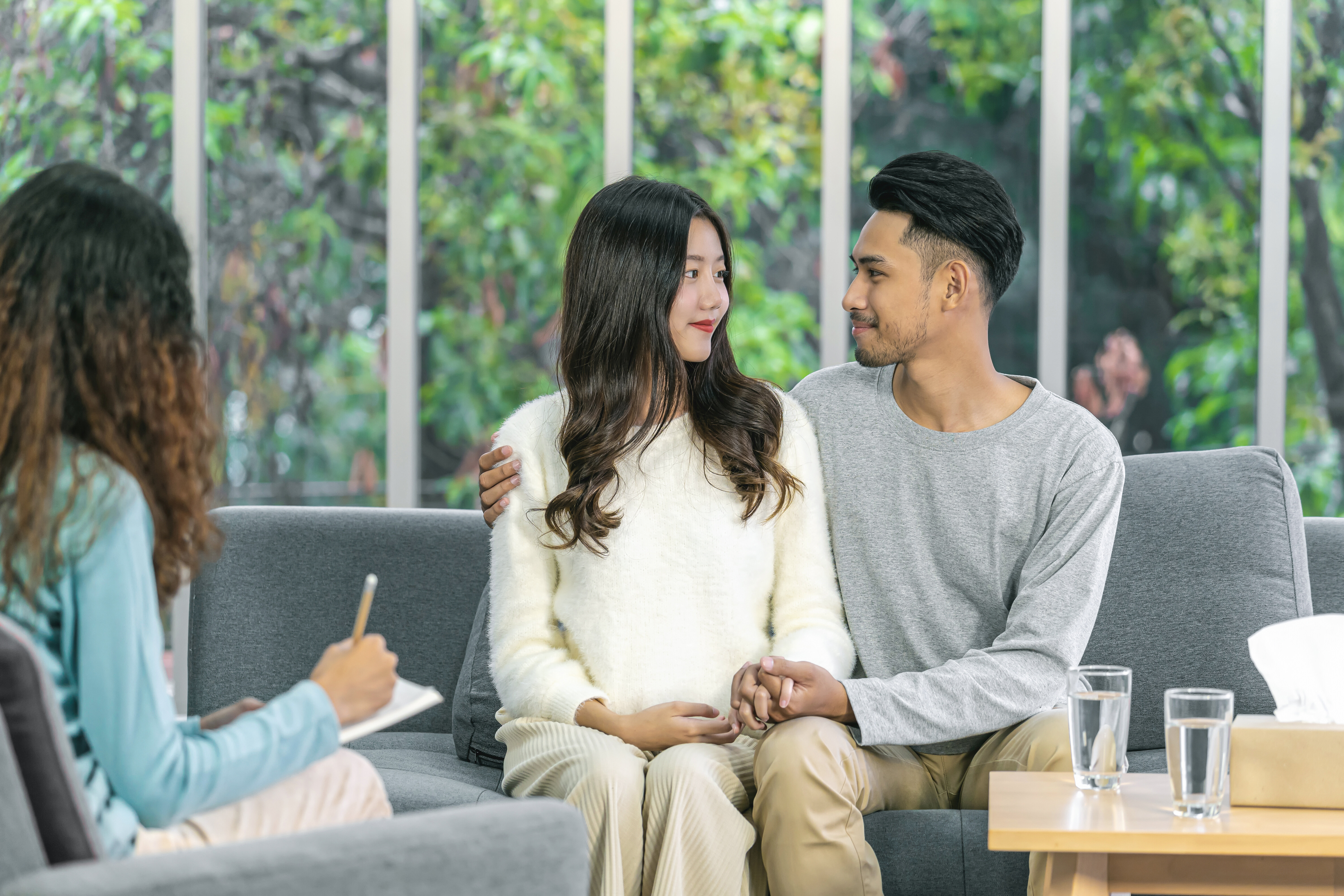 A couple sitting on a couch opposite a couples therapist in Singapore