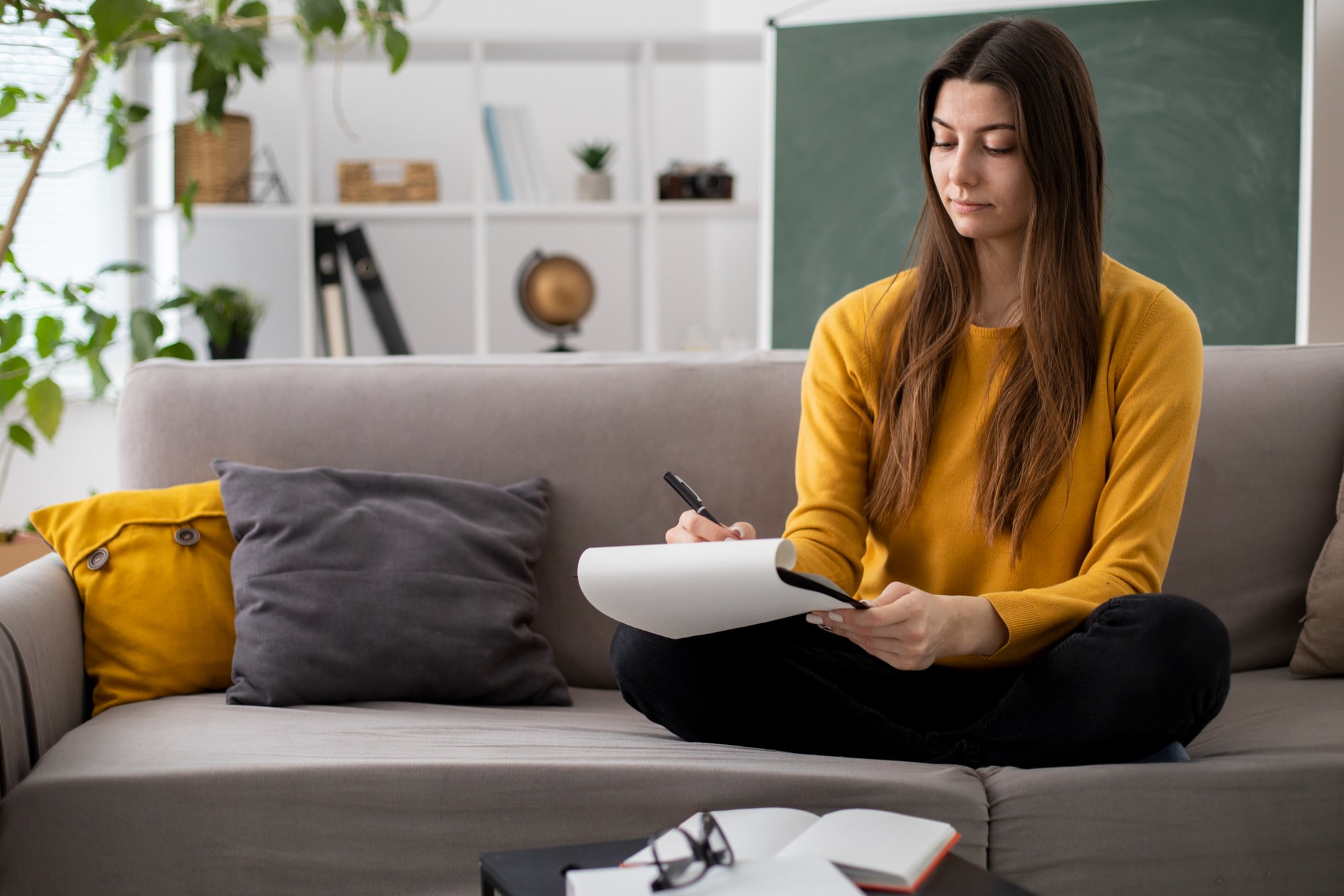 A person sitting on the sofa and writing down their goals for therapy in Singapore.