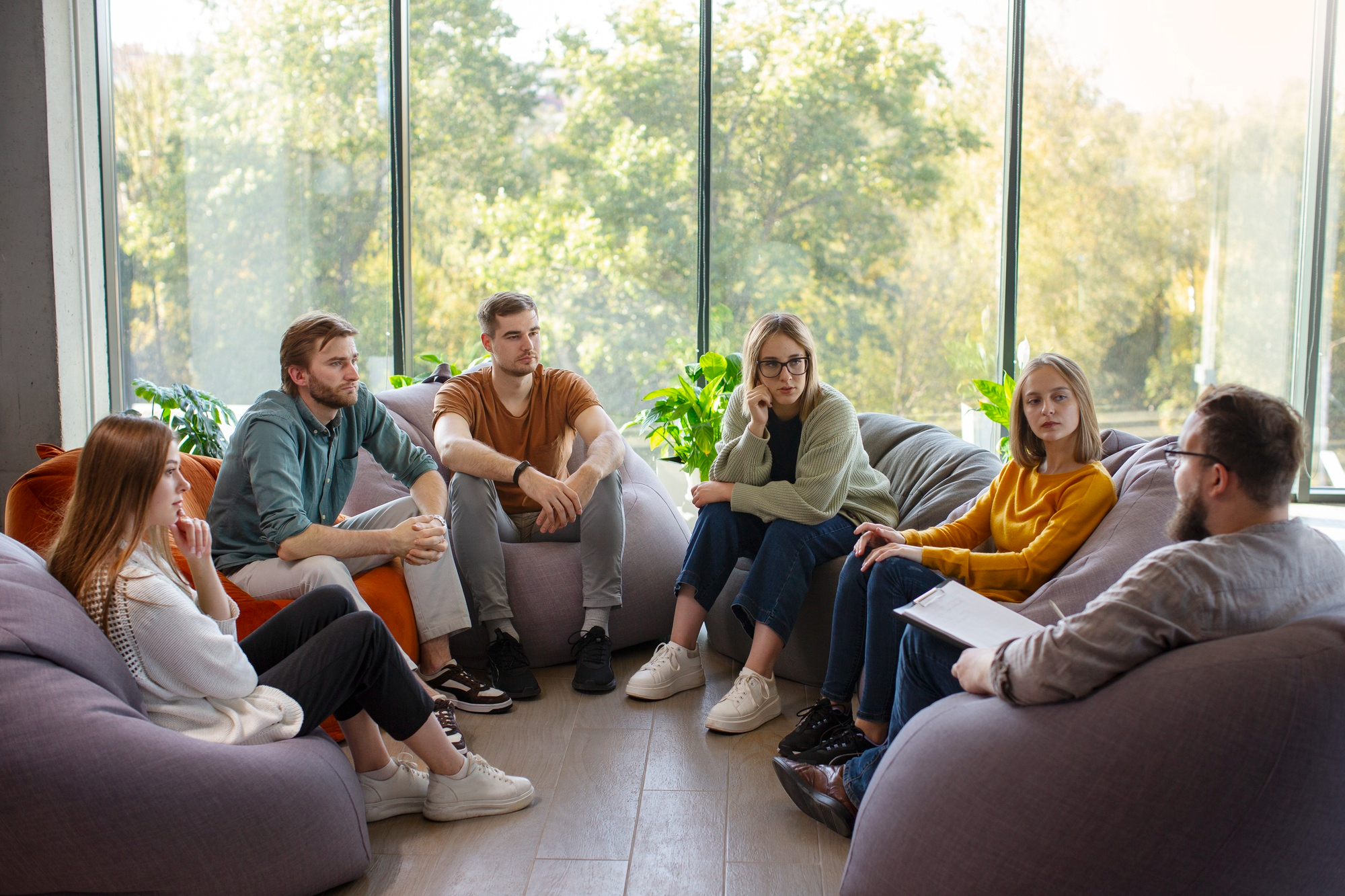 A group of corporate employees engaging in a group therapy session aimed at promoting mental health at work.